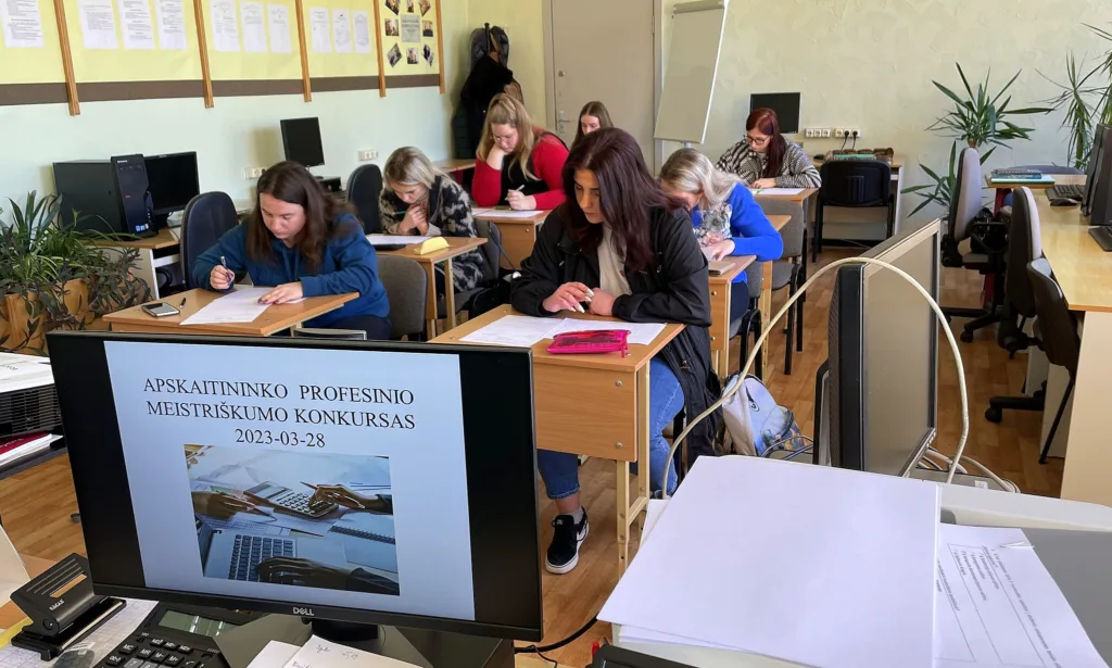 Dalyvės dirba prie užduočių mokyklos kompiuterių klasėje.